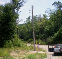 Brad examining a new telephone pole at the bottom of the driveway