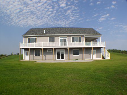 The house, from the back, fully built on a bright and sunny day.