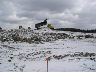 Snowy day with a pile of rocks and a dump truck