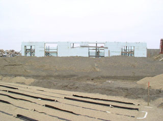 Septic field continues to be exposed in the foreground.  Fill is being added around the sides of the downstairs.