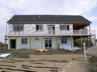 Drywall is leaning against the downstairs exterior wall.  The cold storage has been graveled.  Extra gravel in a pile nearby. Septic, you know the drill.