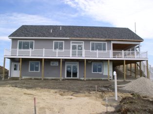 There is now railings on the porch stairs, siding is covering most of the house, and *gasp* the septic field has been filled in with sand